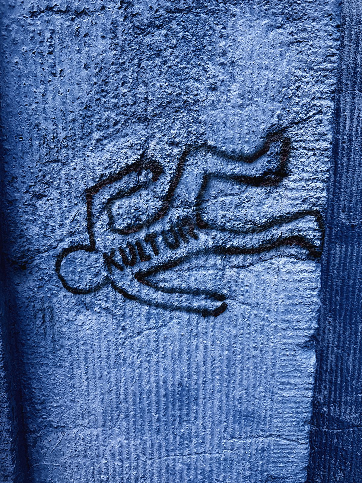 Gesprühter Körperumriss mit Schriftzug Kultur auf blauer Wand
